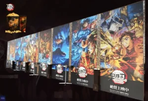 Foto de um banner promocional em um cinema para os filmes da Saga Final de Demon Slayer, ilustrando a análise sobre a divisão do Arco do Castelo Infinito e da Contagem Regressiva para o Amanhecer em uma trilogia.